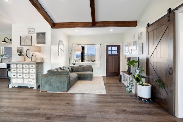 living area with a barn door, recessed lighting, wood finished floors, and beam ceiling