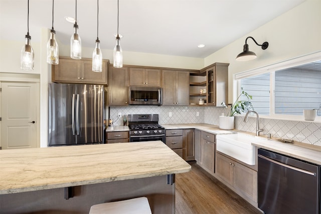 kitchen with open shelves, a sink, stainless steel appliances, a kitchen bar, and tasteful backsplash