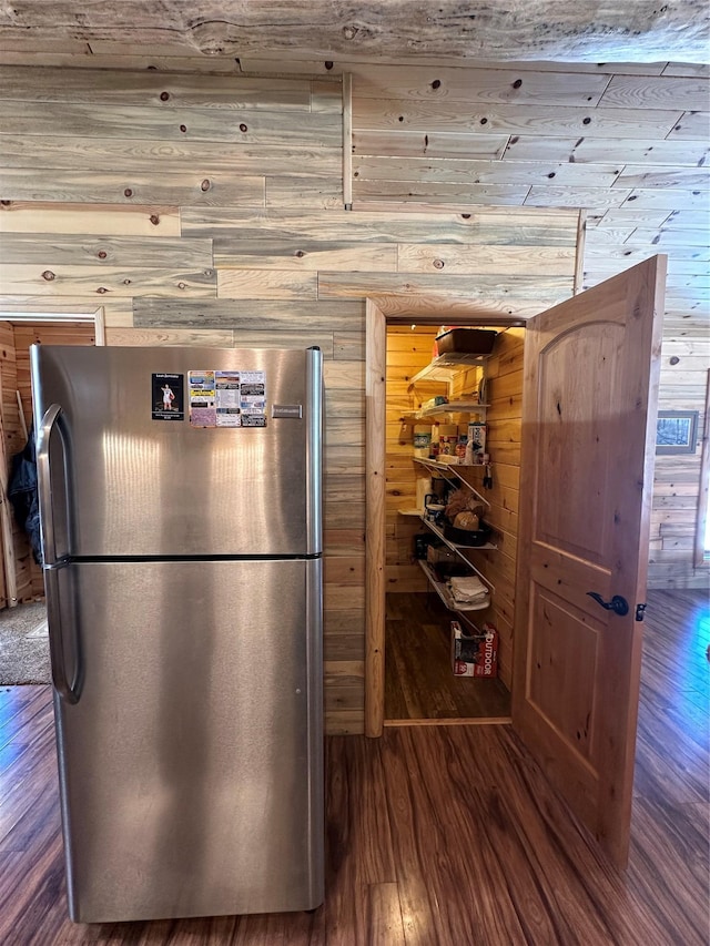 kitchen with wooden walls, freestanding refrigerator, and wood finished floors