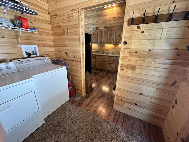 washroom featuring laundry area, dark wood-style flooring, wood walls, and washing machine and clothes dryer