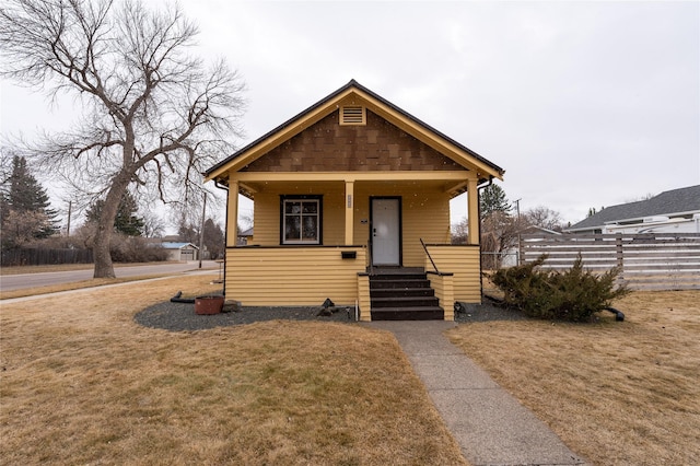 bungalow-style home featuring a porch, a front lawn, and fence