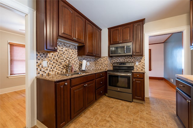 kitchen with a sink, decorative backsplash, light stone countertops, and stainless steel appliances