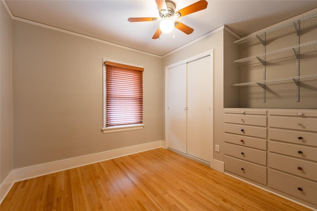 unfurnished bedroom with ceiling fan, baseboards, light wood-type flooring, ornamental molding, and a closet