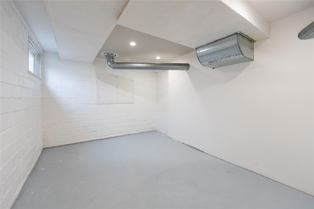 below grade area featuring a wall unit AC, concrete block wall, and recessed lighting