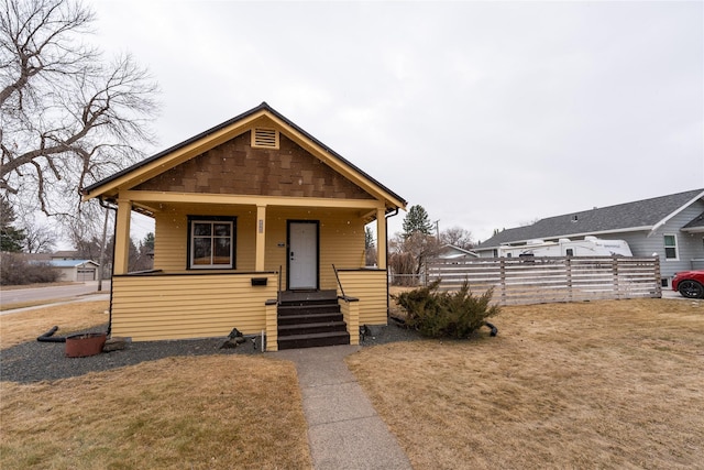 view of front of property featuring a porch, a front lawn, and fence