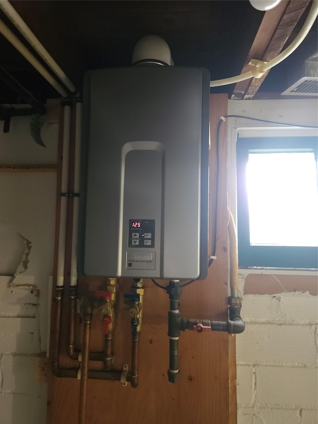 utility room with tankless water heater and visible vents