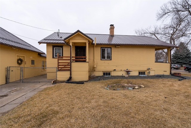 view of front of property featuring a chimney, metal roof, a front yard, and fence