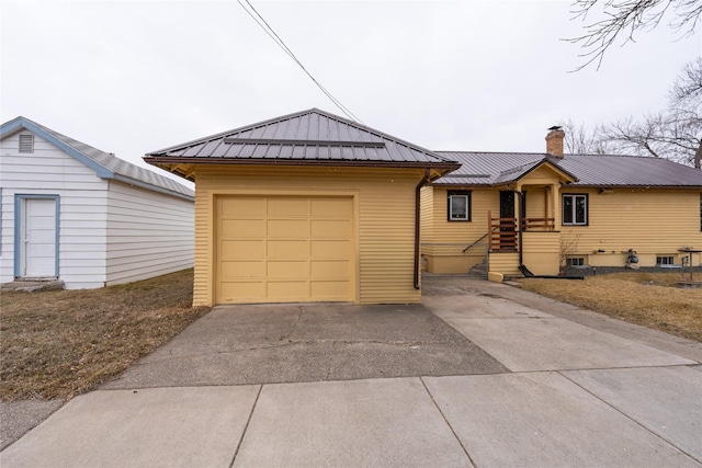 view of front of house featuring a chimney, concrete driveway, and metal roof