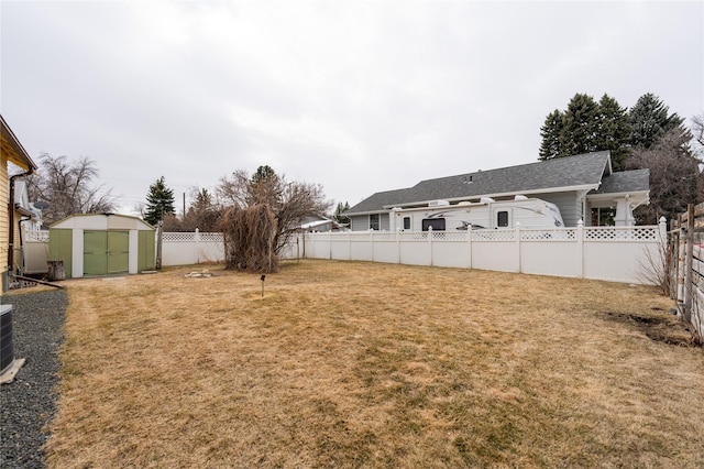 view of yard featuring a storage shed, a fenced backyard, and an outdoor structure