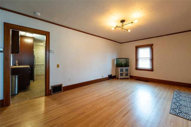 unfurnished room with visible vents, light wood-style flooring, baseboards, and ornamental molding