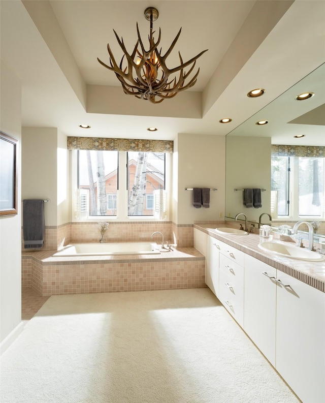 bathroom with a sink, a tray ceiling, and a garden tub