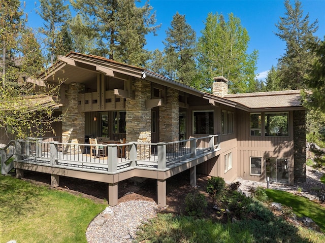 back of house featuring board and batten siding, a chimney, and a deck