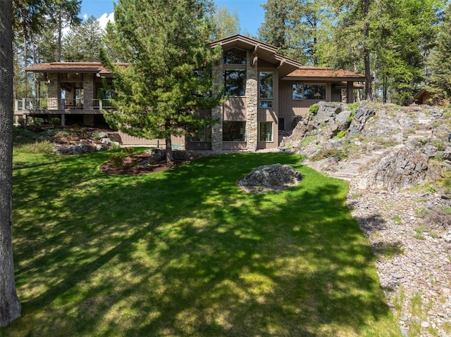 rear view of property with a yard and stone siding