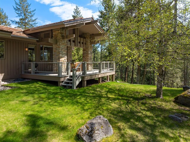 rear view of house featuring stone siding, a lawn, board and batten siding, and a deck