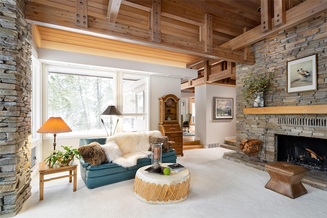 living area with carpet, visible vents, beam ceiling, a stone fireplace, and wood ceiling