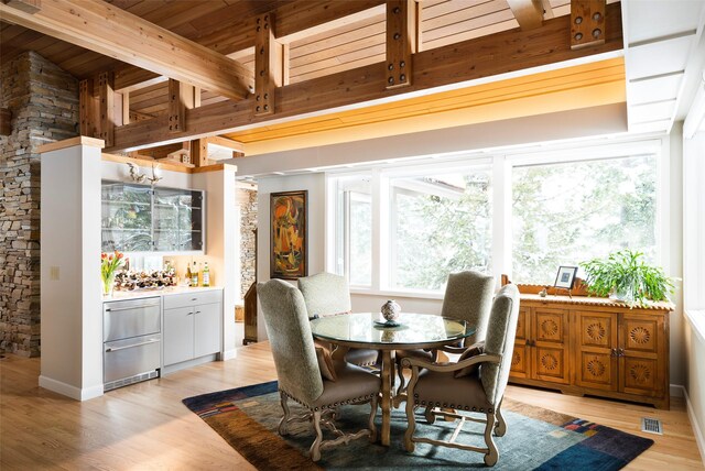 dining area featuring visible vents, beam ceiling, wooden ceiling, a dry bar, and light wood-type flooring