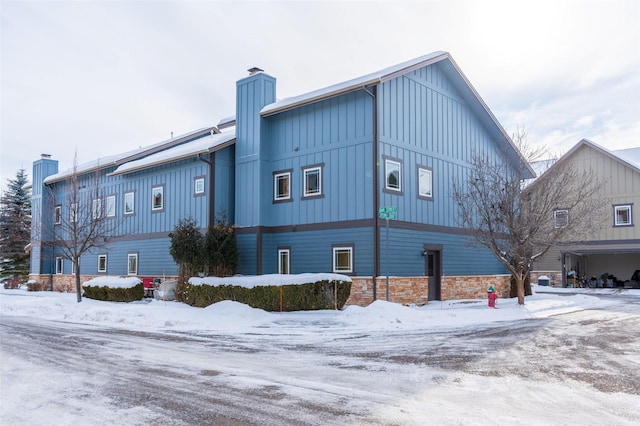 119 Oak St, Whitefish, MT 59937 - view of snow covered exterior with a chimney, board and batten siding, and stone siding