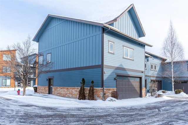 119 Oak St, Whitefish, MT 59937 - view of snowy exterior with board and batten siding, a garage, and stone siding