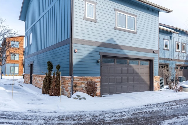 119 Oak St, Whitefish, MT 59937 - view of snow covered exterior featuring board and batten siding, an attached garage, and stone siding