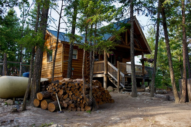 view of front of house featuring log veneer siding, metal roof, and stairway