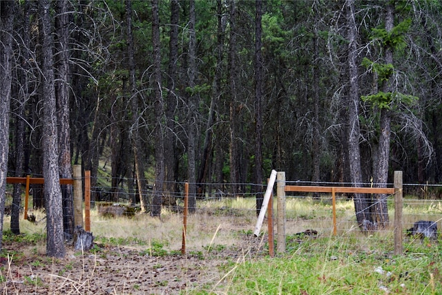 view of yard with a forest view and fence