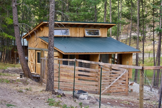 view of outbuilding featuring an exterior structure, a forest view, and an outdoor structure