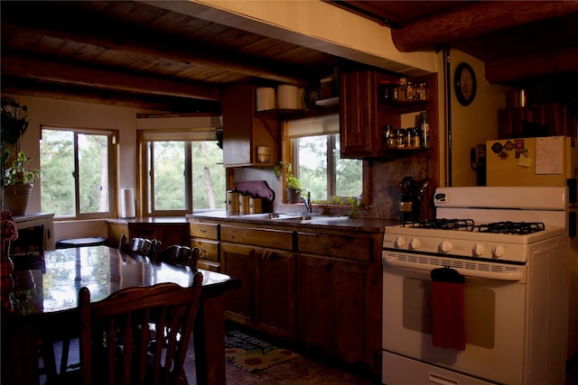 kitchen featuring beamed ceiling, wood ceiling, white gas range, and a sink