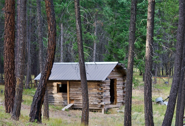 view of front of house featuring an outdoor structure, a view of trees, and metal roof