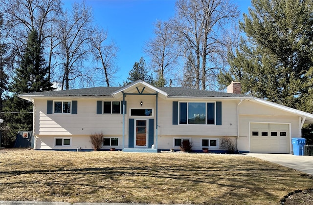 bi-level home with driveway, a chimney, a garage, and a front yard