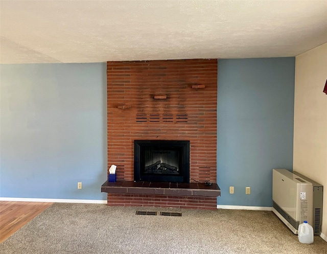 unfurnished living room featuring visible vents, a textured ceiling, carpet flooring, baseboards, and a brick fireplace