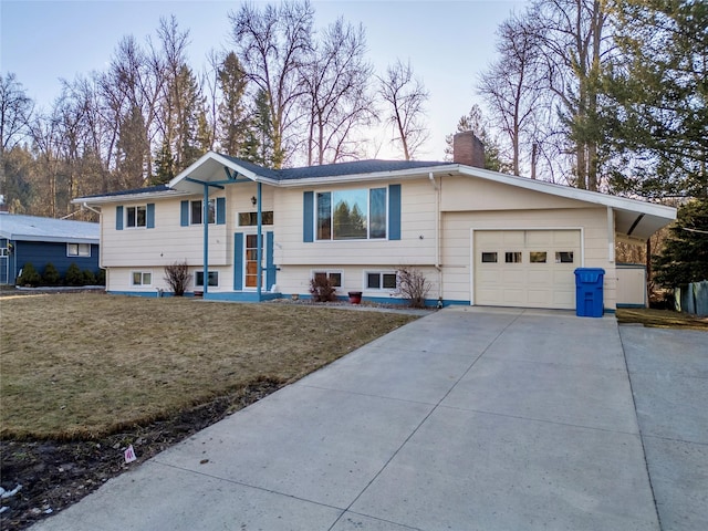 raised ranch with a front lawn, a garage, driveway, and a chimney