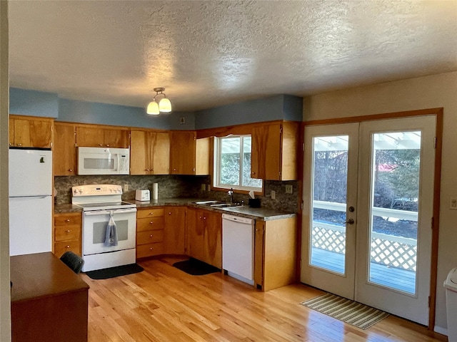 kitchen featuring dark countertops, backsplash, french doors, white appliances, and light wood-style floors