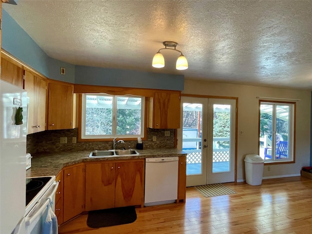 kitchen with a wealth of natural light, light wood-type flooring, a sink, french doors, and white appliances