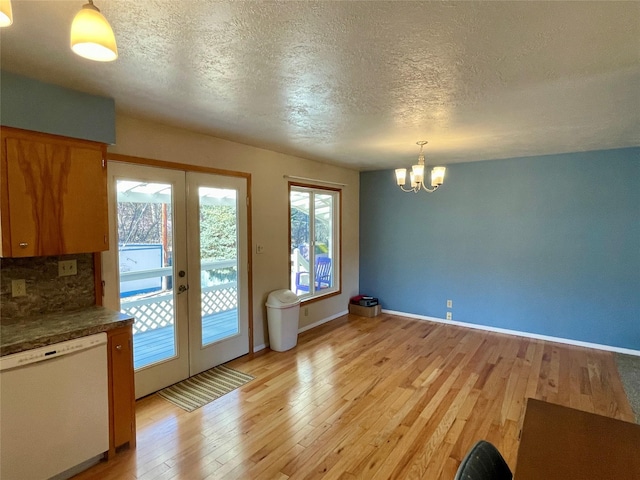 1408 Nevada Ave, Libby, MT 59923 - unfurnished dining area with french doors, a chandelier, light wood-type flooring, healthy amount of natural light, and a textured ceiling