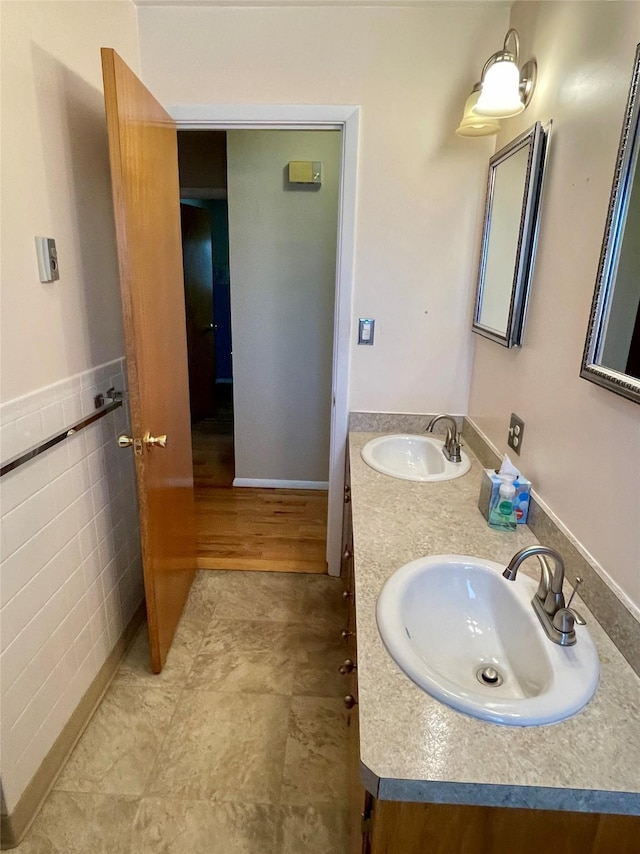 bathroom featuring a sink, tile walls, and double vanity