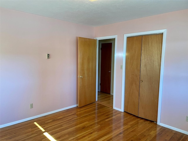 unfurnished bedroom with a closet, baseboards, and wood finished floors