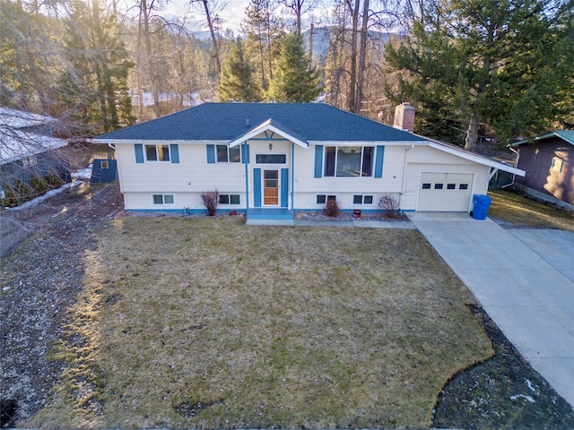 split foyer home featuring a shingled roof, concrete driveway, a front yard, a chimney, and an attached garage