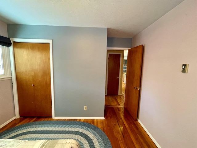 unfurnished bedroom with wood finished floors, baseboards, and a closet