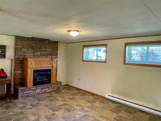 basement with a wealth of natural light, a baseboard radiator, a glass covered fireplace, and crown molding