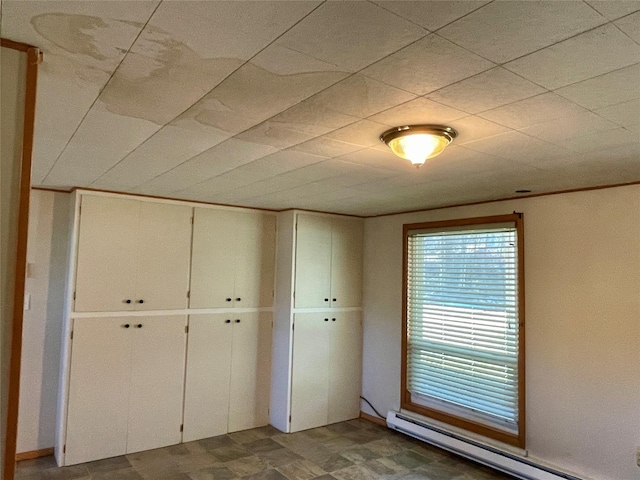 unfurnished bedroom with a closet, tile patterned floors, and a baseboard heating unit