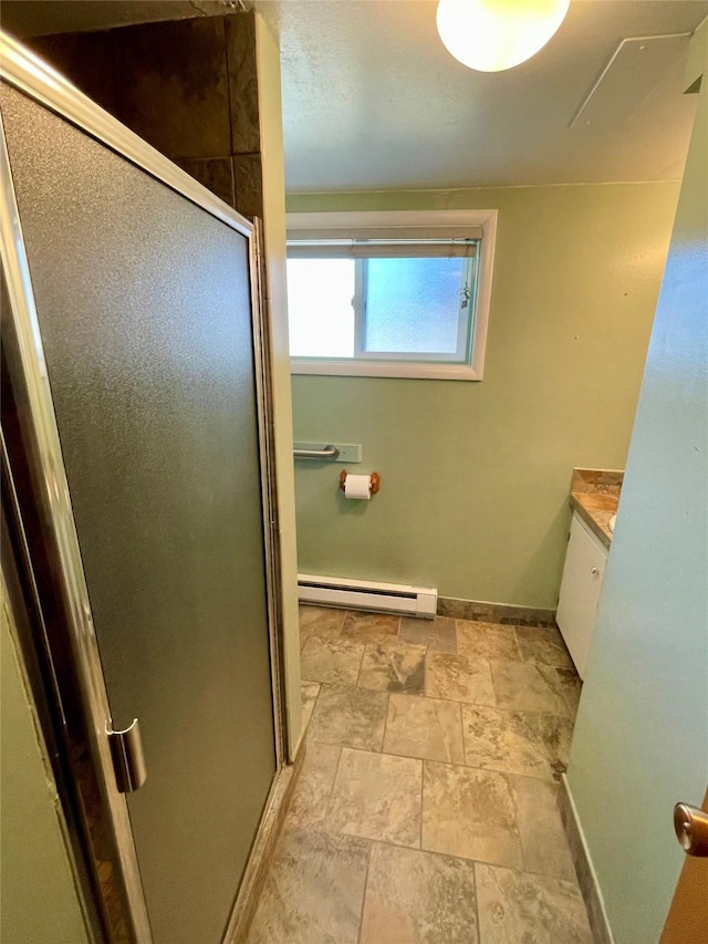 full bath with stone finish flooring, a baseboard heating unit, baseboards, a stall shower, and vanity