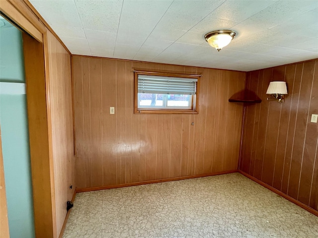 unfurnished room with wooden walls, light floors, and baseboards