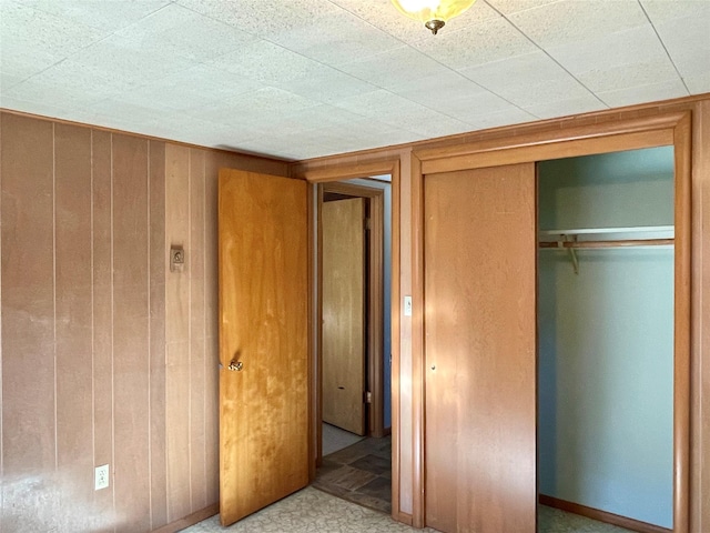 unfurnished bedroom featuring a closet and wood walls