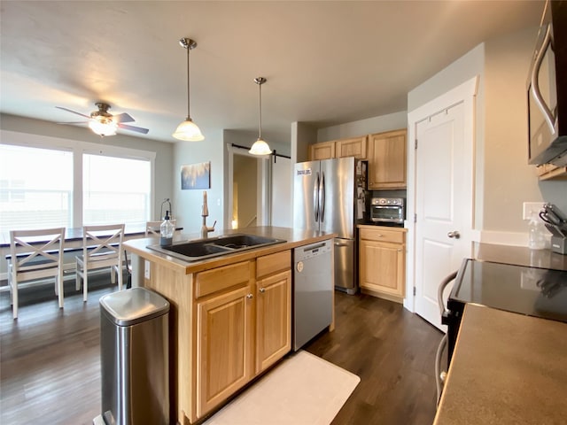 kitchen with a sink, light brown cabinetry, a center island with sink, stainless steel appliances, and dark wood-style flooring