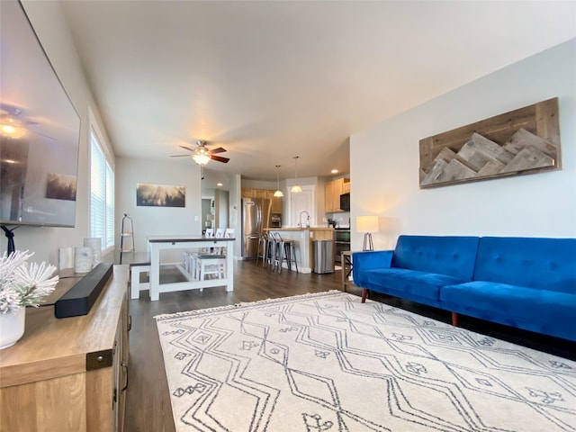 living area with ceiling fan and dark wood finished floors