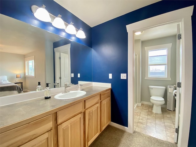 bathroom featuring a wealth of natural light, baseboards, toilet, and vanity