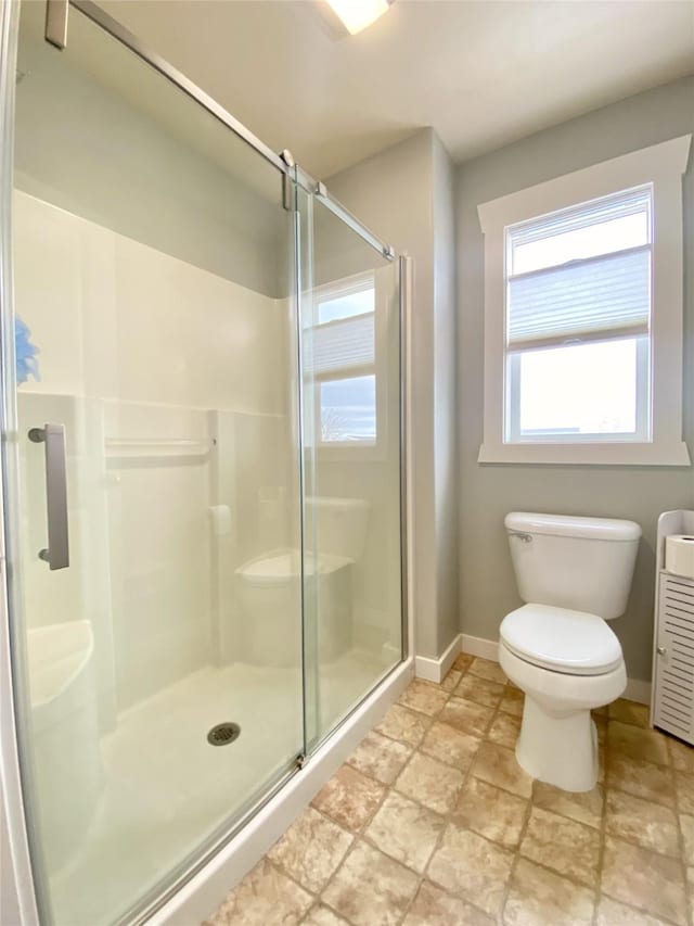 bathroom with baseboards, toilet, and a shower stall