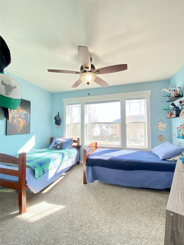 carpeted bedroom featuring multiple windows and ceiling fan