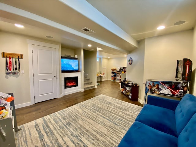 living room with visible vents, baseboards, recessed lighting, a warm lit fireplace, and wood finished floors