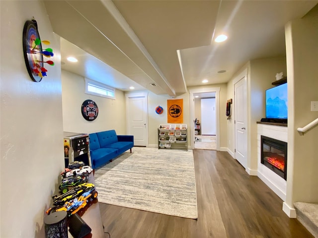 living area featuring a glass covered fireplace, recessed lighting, wood finished floors, and baseboards